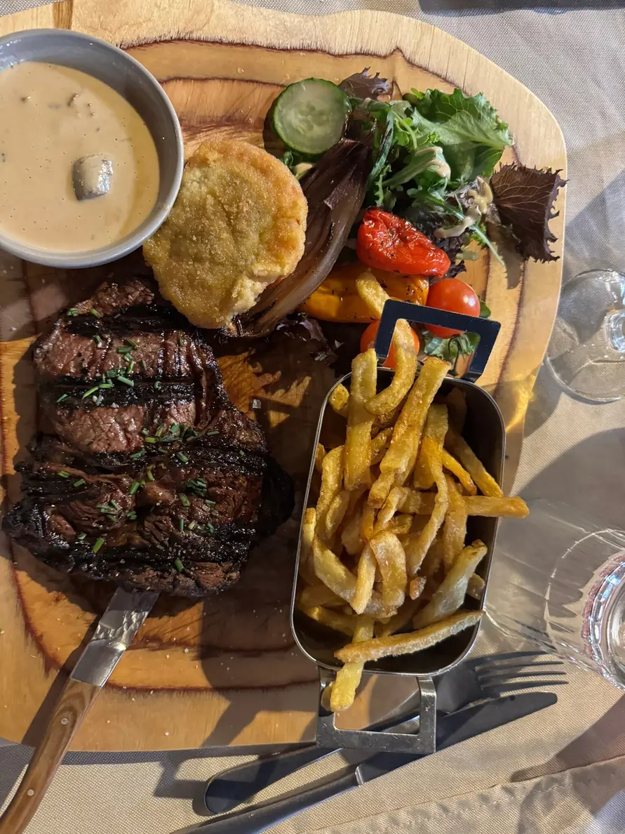 Pièce de bœuf grillée, frites en barquette et sauce, servies sur planche