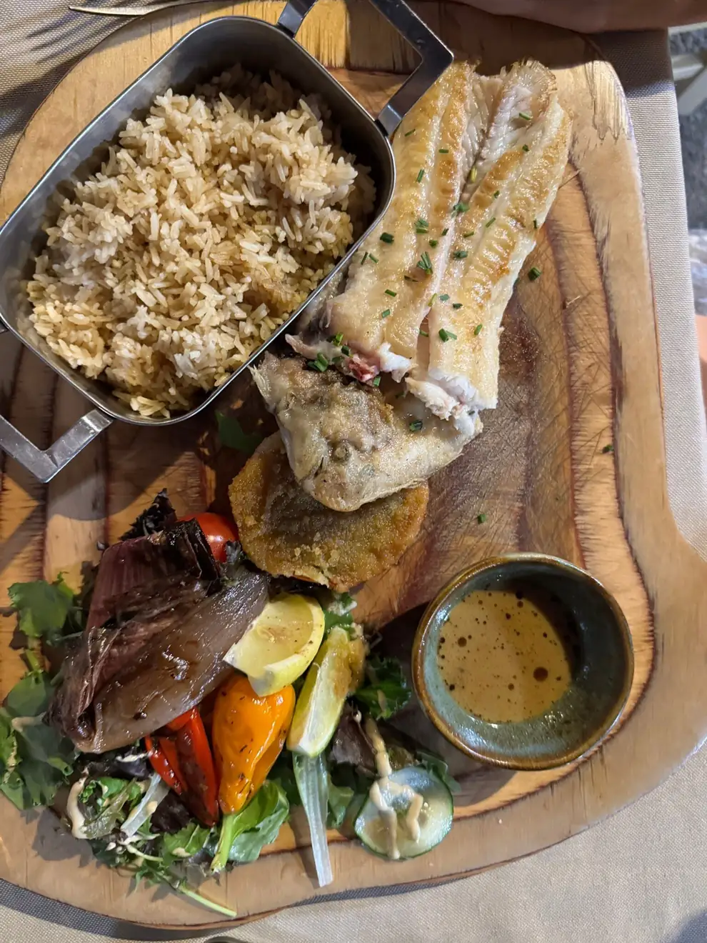 Poisson sur planche de bois, riz, légumes grillés et sauce